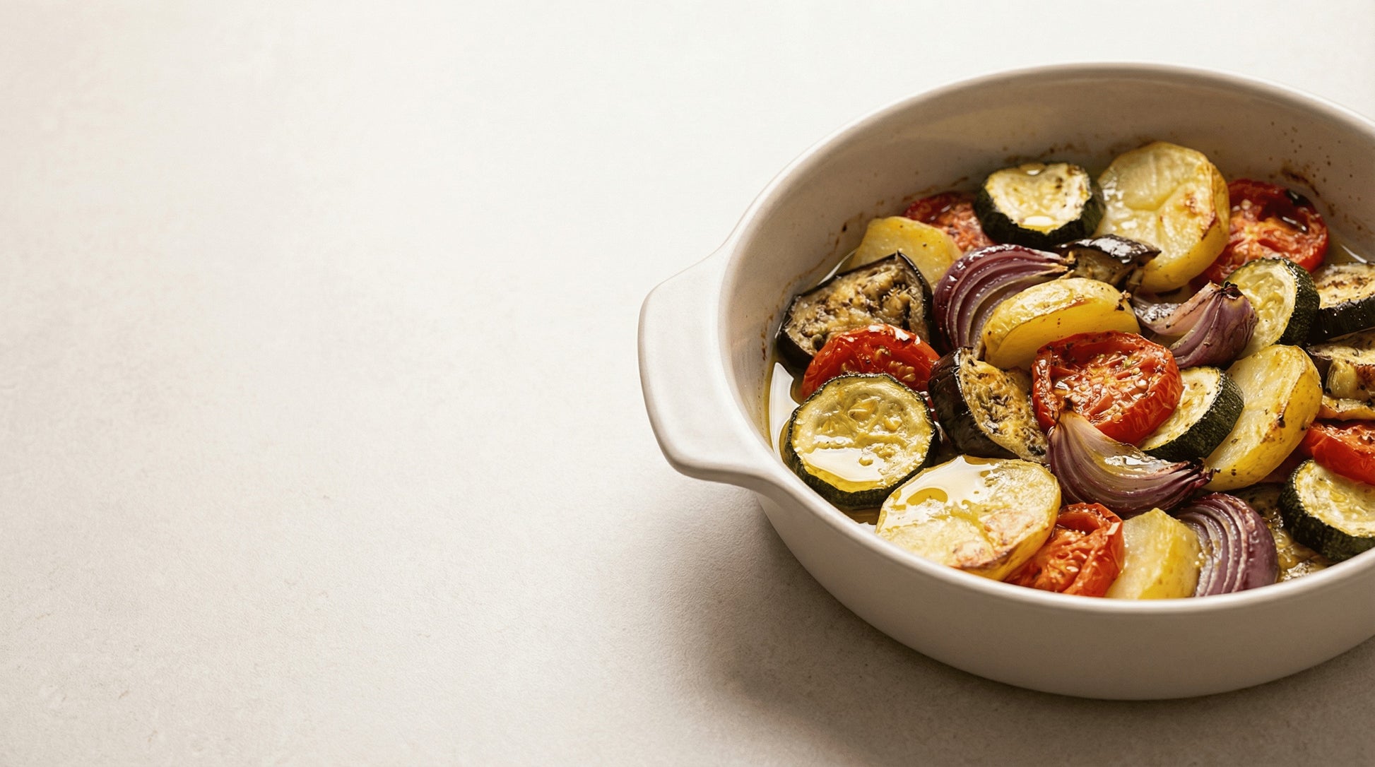 Briam Ofengemüse in einer Form mit Olivenöl – mediterran serviert.