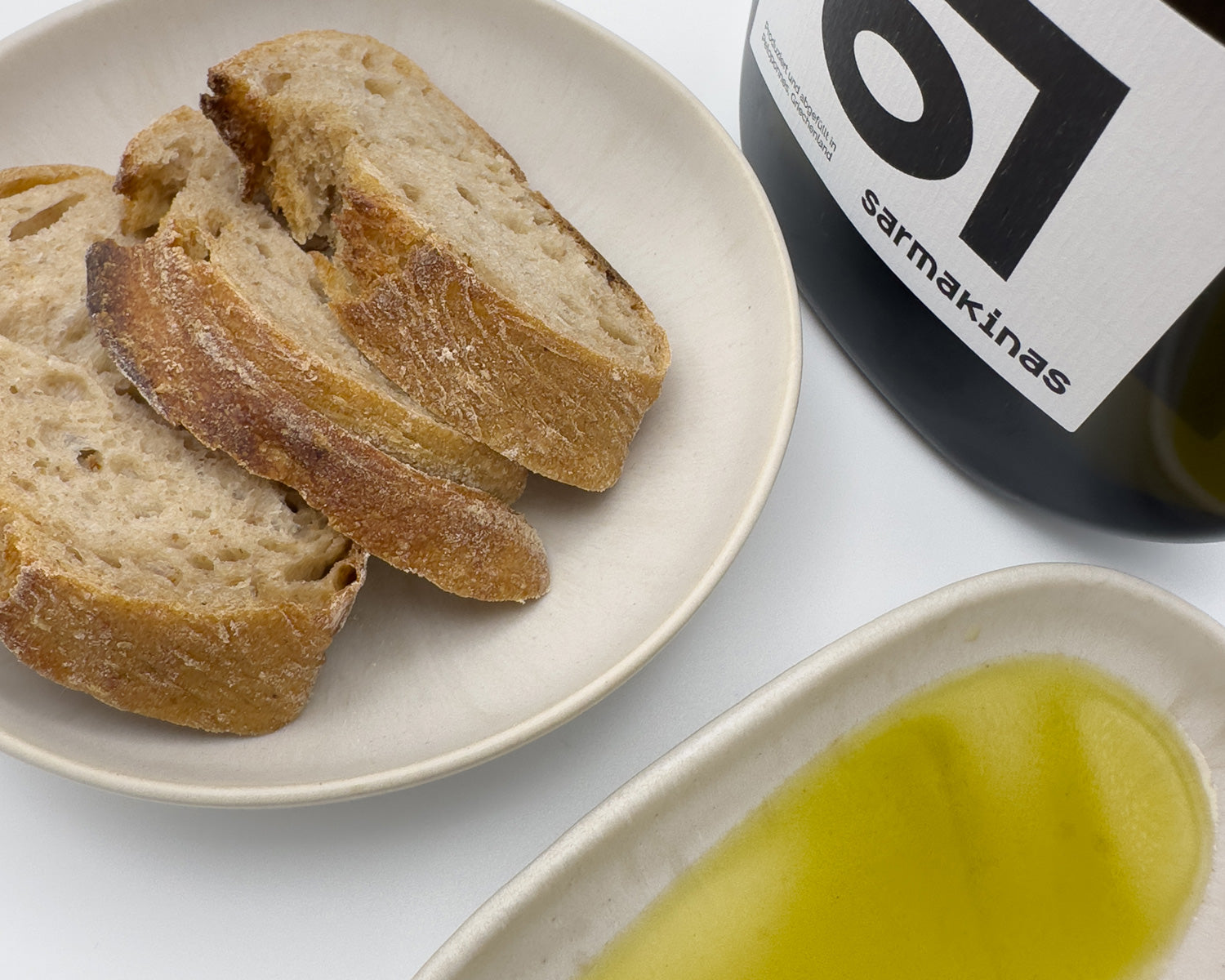 Sarmakinas Olivenölflasche mit Brot und Olivenöl im Schälchen