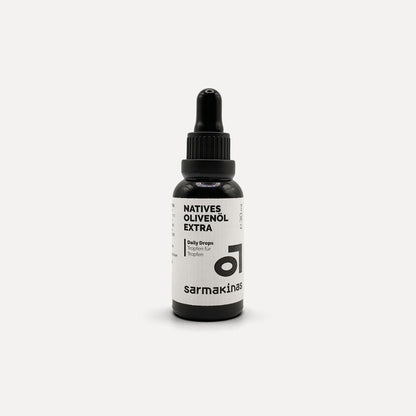 Sarmakinas Daily Drops: 30 ml natives Olivenöl extra in schwarzer Pipettenflasche, sortenreines Koroneiki-Olivenöl, minimalistisch fotografiert vor hellem Hintergrund