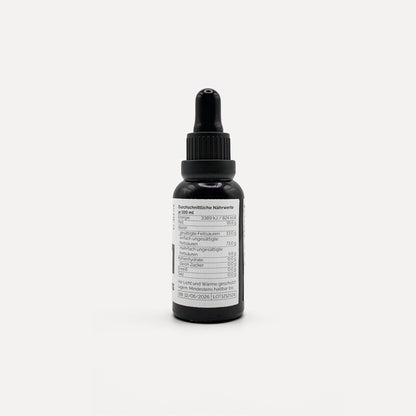 Sarmakinas Daily Drops: 30 ml natives Olivenöl extra in schwarzer Pipettenflasche, sortenreines Koroneiki-Olivenöl, minimalistisch fotografiert vor hellem Hintergrund.